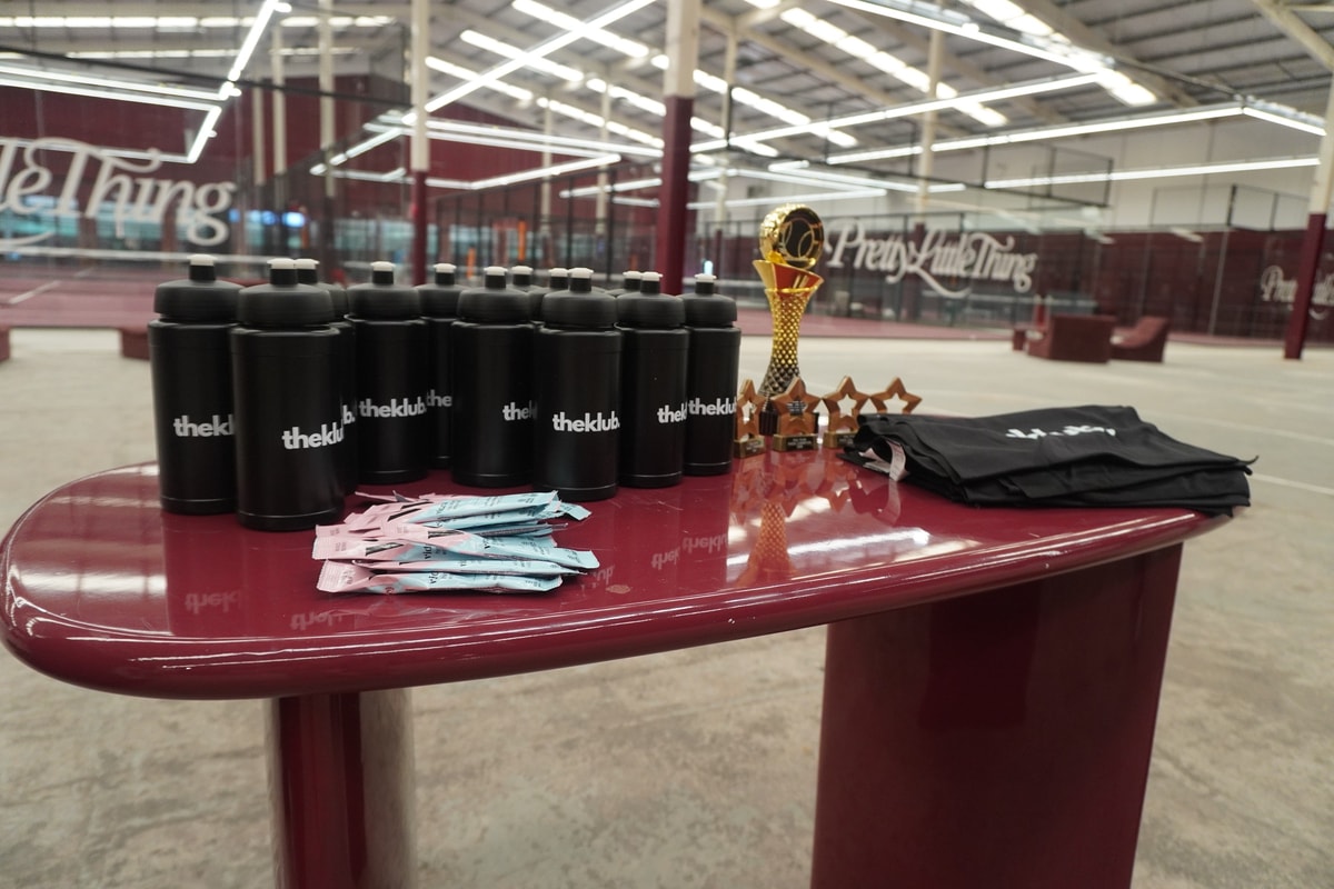 theKlub-branded bottles, a trophy and goody bags laid out for a corporate padel tournament