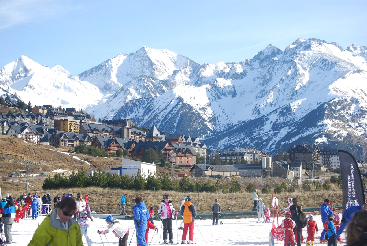 The village of Formigal below the snowy peaks of the Valle de Tena, with a ski school on the nursery slope