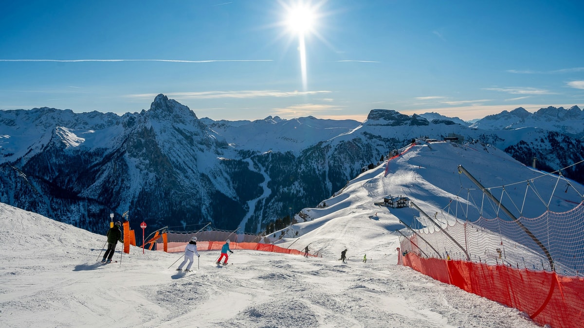 Skiers on a sunlit piste in the Dolomites above Rocca Pietore